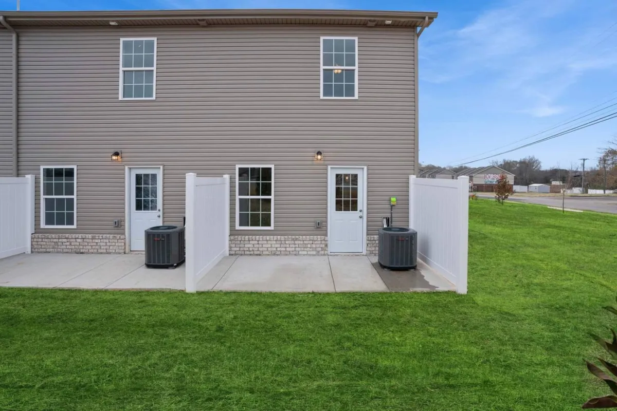 A paved walkway flanked by two white fences and a green lawn, this image evokes the accessibility and friendliness of the neighborhood. The scene is set for sunny afternoons, outdoor gatherings, or a tranquil retreat after experiencing the city's energy.