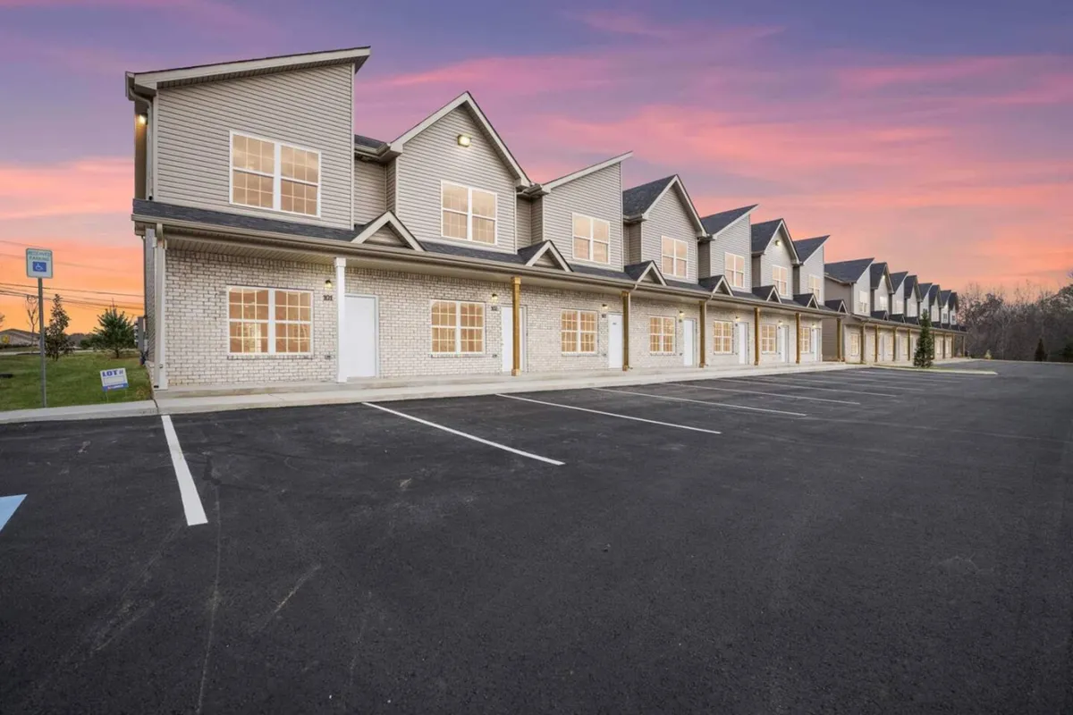 This image captures a row of inviting townhouses with large windows and gabled roofs, bathed in the warm glow of sunset. The setting hints at community life and offers a glimpse of the upscale, peaceful neighborhood just outside the city's vibrant core.