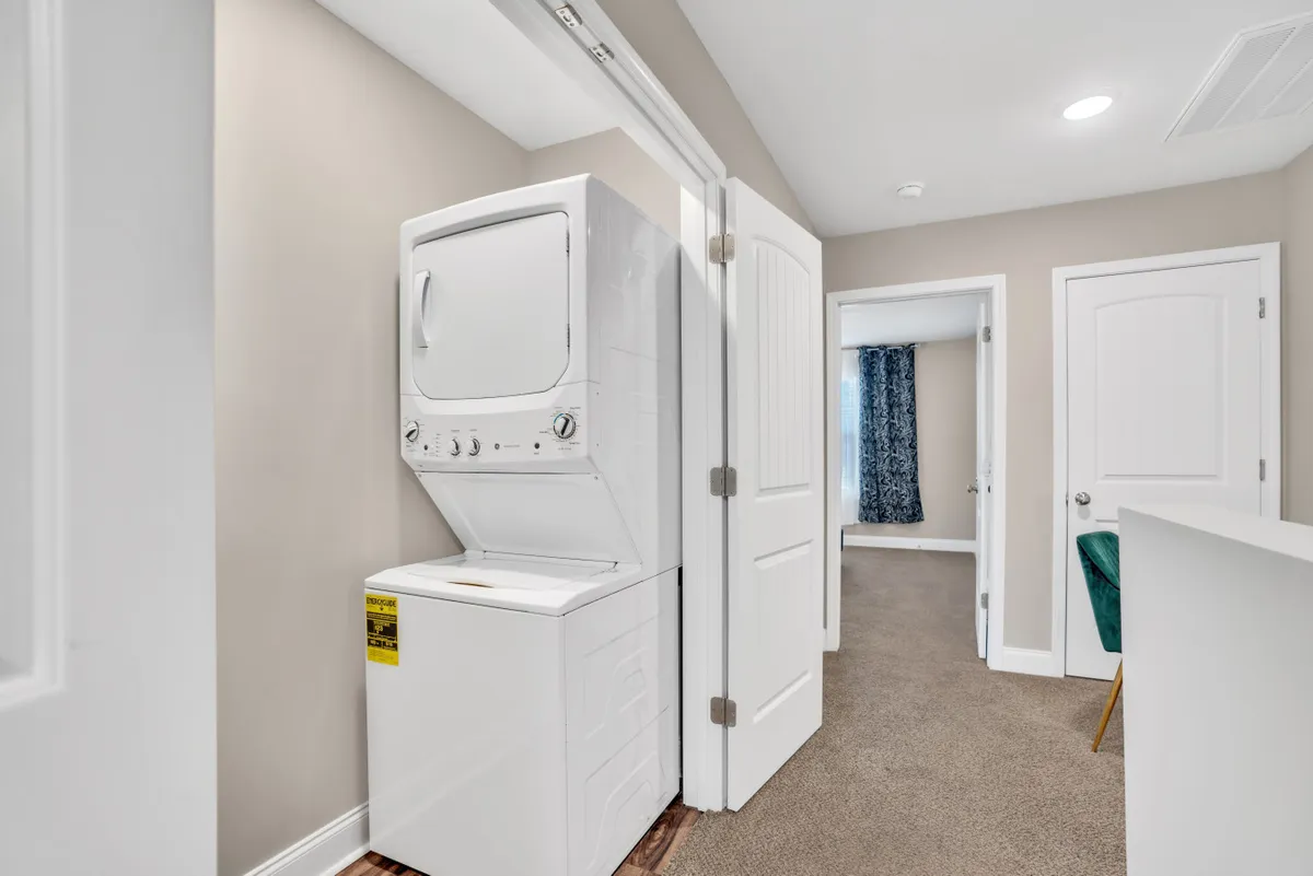 This image features a washer and dryer unit neatly arranged in a dedicated laundry area. The space is adorned with decorative curtains and a door leading to an adjacent room, giving a sense of practical convenience within the home.