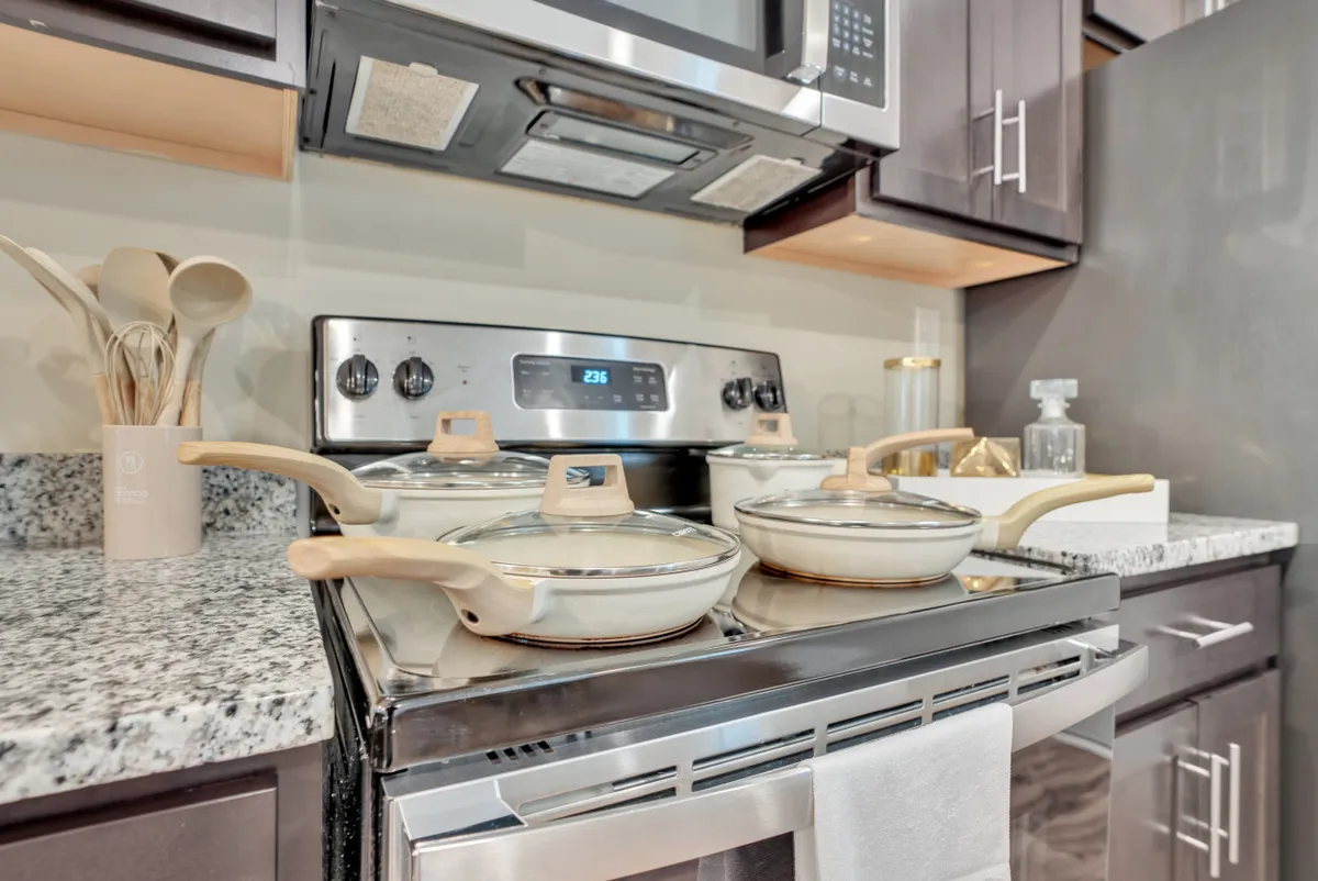 A modern kitchen with a stainless steel stove, granite countertop, and essential cooking utensils. The scene is set for meal preparation and shared experiences, with ample space for cooking and gathering.