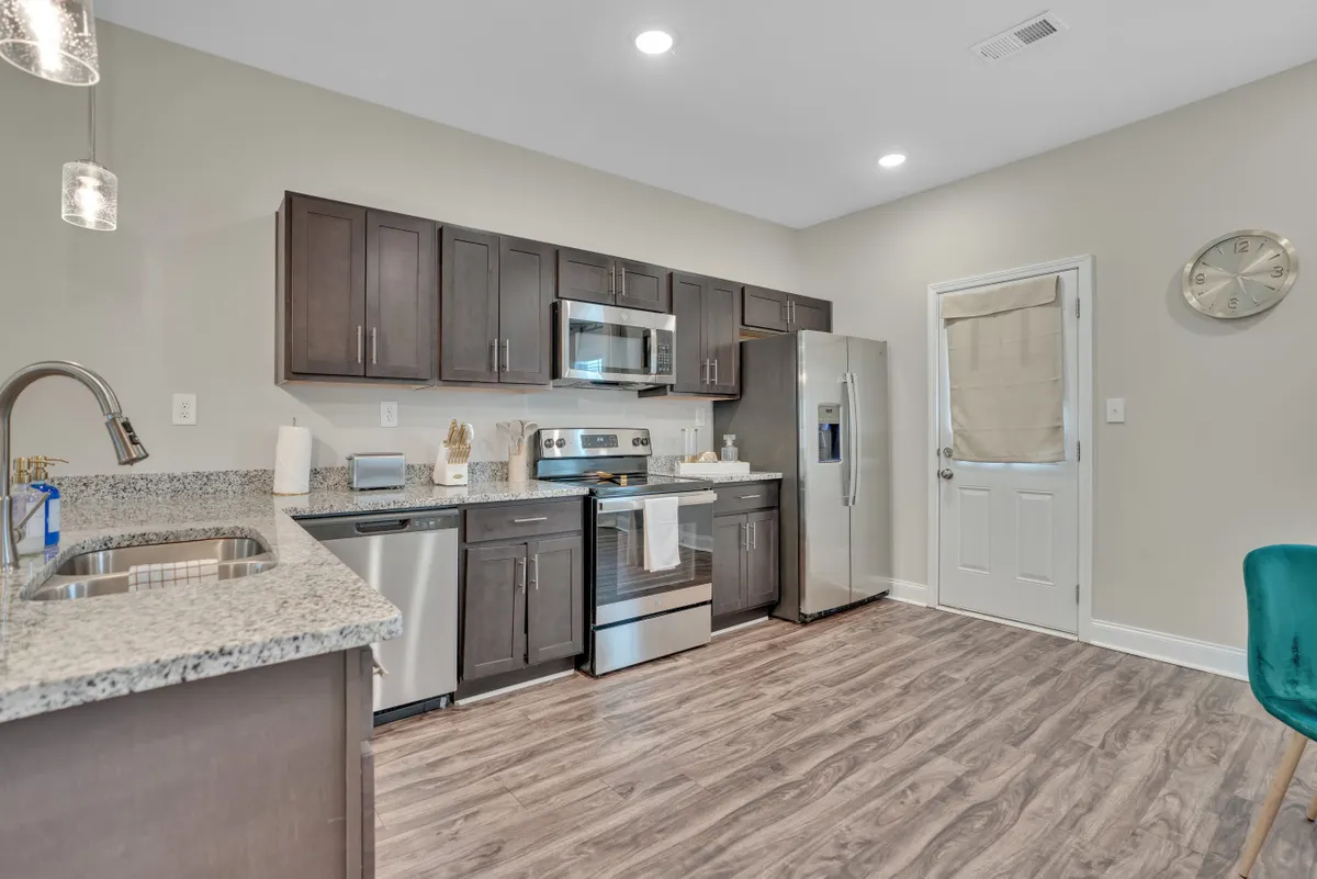 A modern kitchen with sleek granite countertops, dark wood cabinetry, and stainless steel appliances. The space is large enough for family gatherings, meal preparation, and socializing, enhancing the sense of a welcoming home environment.